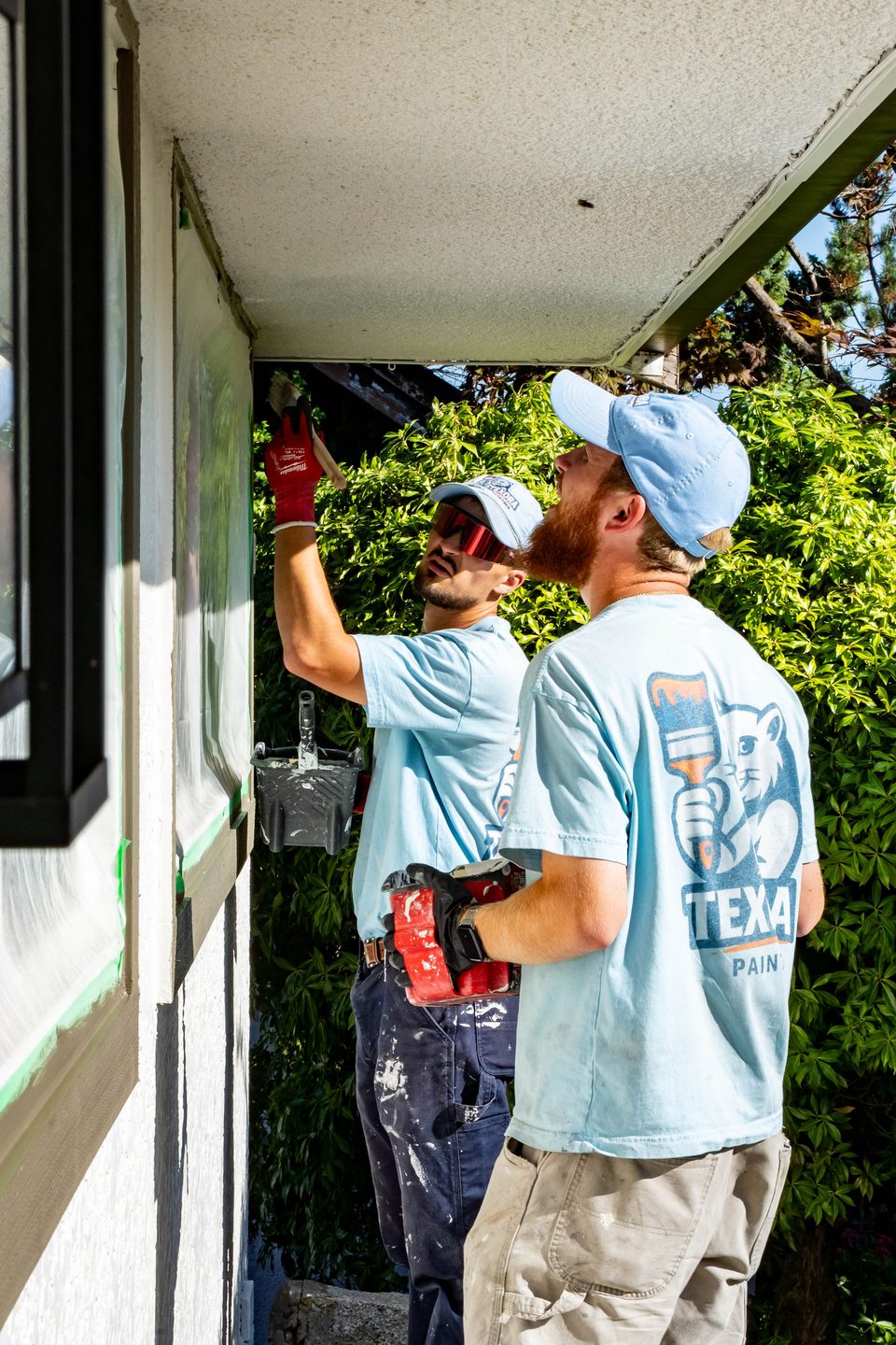 Two Texora Painting crew members painting the exterior window trim of a Tsawwassen home