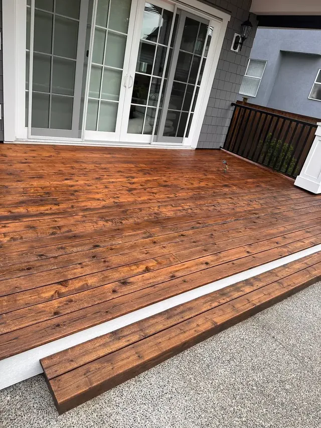 Deck boards refinished in a warm cedar stain beside white sliding doors