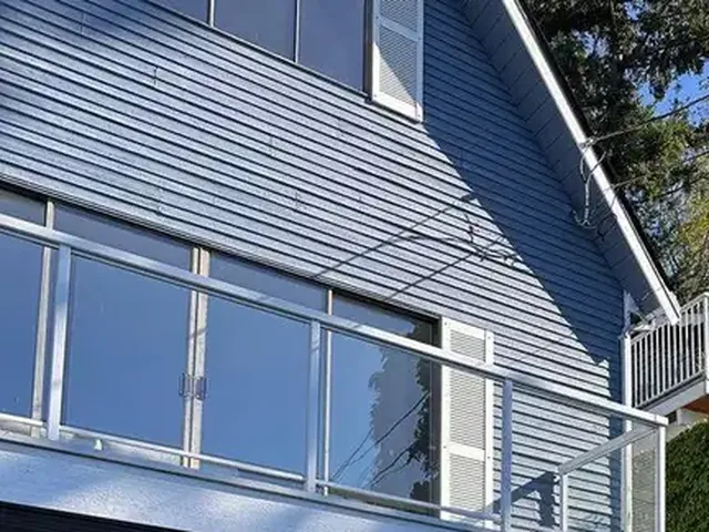 White louvred shutter beside sliding glass doors on weathered blue siding, before repainting