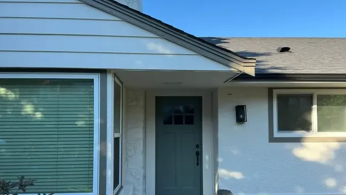 Front of a home repainted with white stucco and an olive-green door