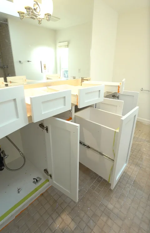 Bathroom vanity in white with every drawer and door open during refinishing