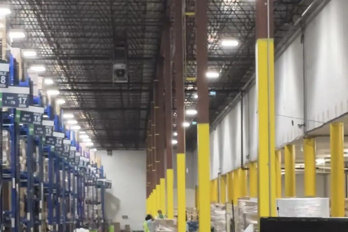Interior of a warehouse with steel racking, safety bollards and high-bay ceiling, the kind of facility Texora Painting & Drywall coats